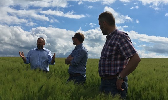 Andrew Booth stood in a field talking to two men.